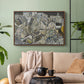 Walnut floater framed canvas featuring a stylized urban composition with geometric structures and muted tones, displayed above a sofa in a modern living room.