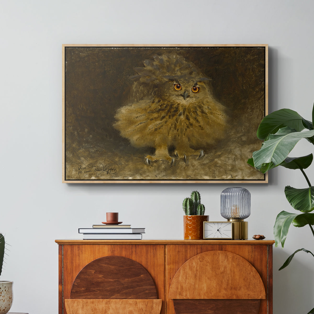 An Eagle Owl (Berguv), 1905 by Bruno Liljefors in a natural wood floater framed canvas featuring a large owl perched on branch in shadowy natural forest setting, displayed above a wood console cabinet.