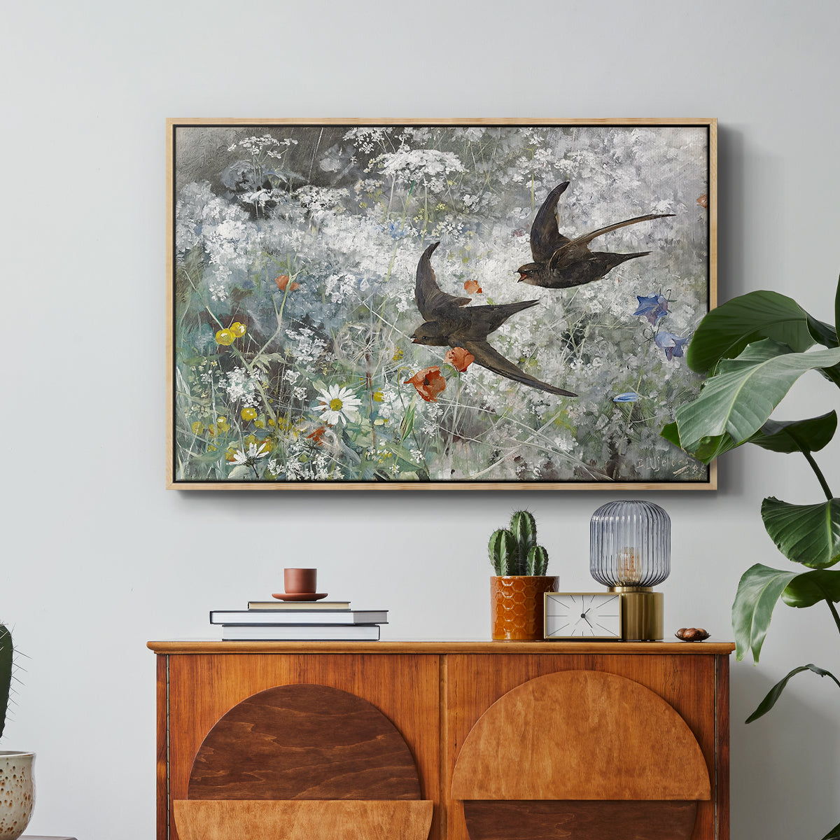 Common Swifts, 1886 by Bruno Liljefors in a natural wood floater framed canvas featuring a flock of birds in flight soaring across open sky above landscape, displayed above a wood console cabinet.