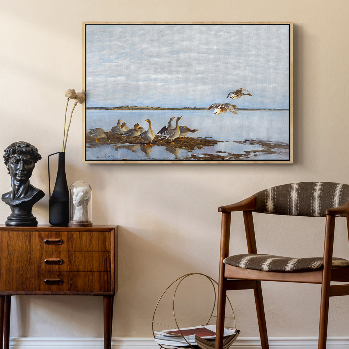 Greylag Geese (Grågäss), 1922 by Bruno Liljefors as a natural wood floater framed canvas featuring a realistic wildlife scene of geese in calm outdoor environment, styled above a mid-century console in a contemporary living area.