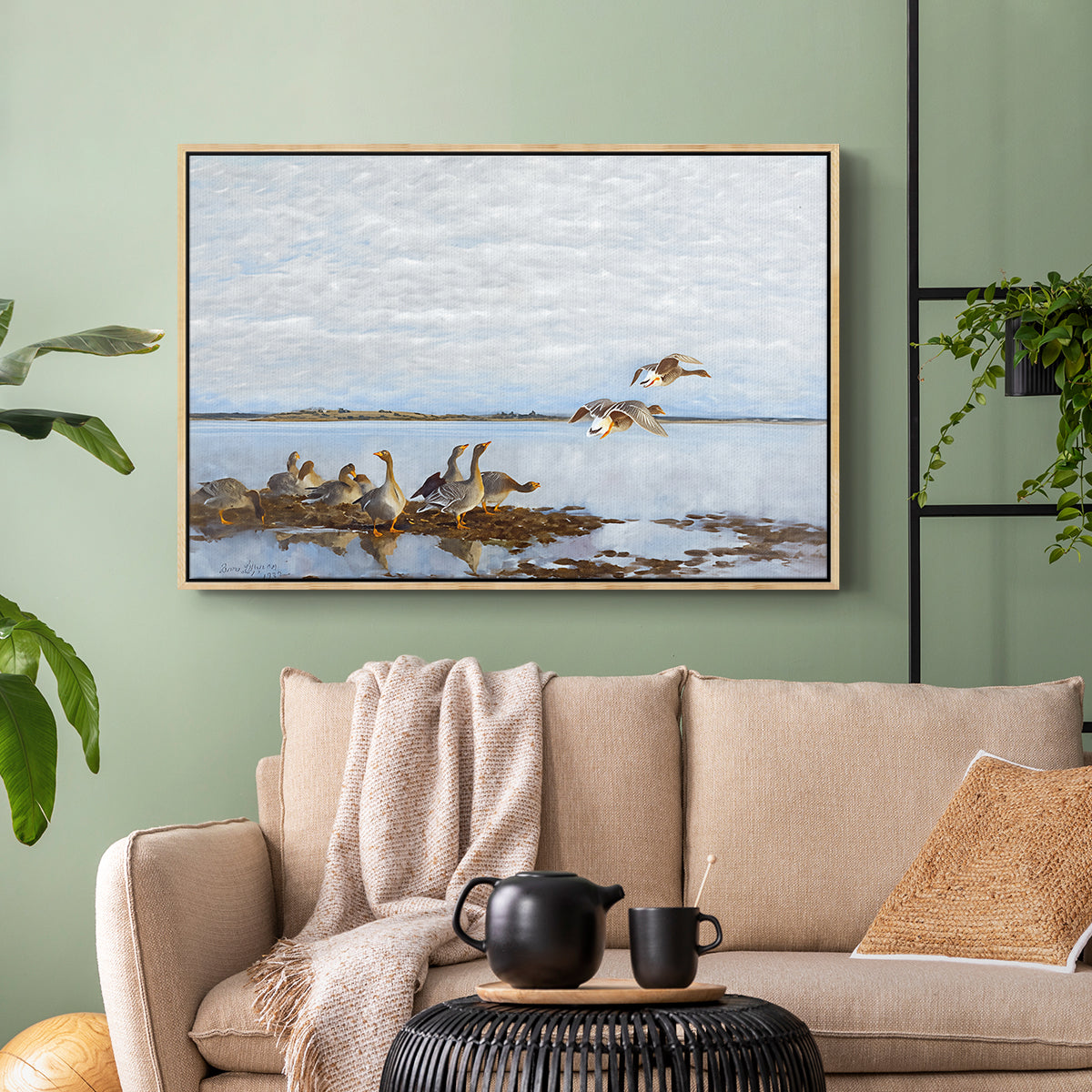 Natural wood floater framed canvas featuring a flock of geese positioned along marshy terrain, displayed above a sofa in a modern living room.
