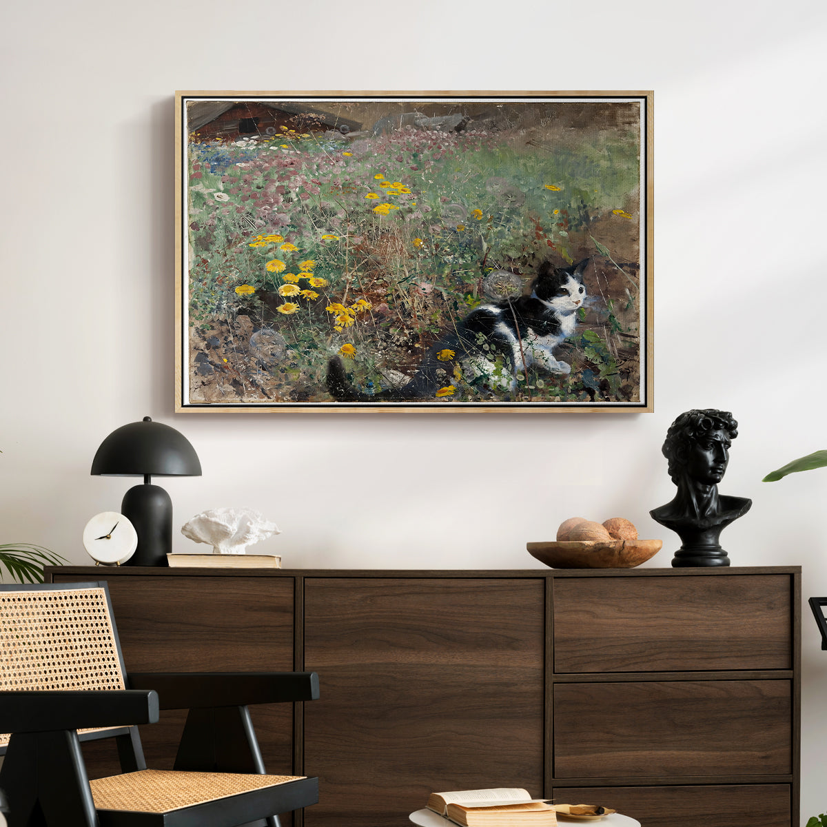 Cat on a Flowery Meadow, 1887 by Bruno Liljefors displayed in a natural wood floater framed canvas above a dark wood credenza in an entryway.