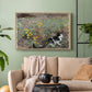 Natural wood floater framed canvas featuring a naturalistic depiction of cat in blooming countryside setting, displayed above a sofa in a modern living room.