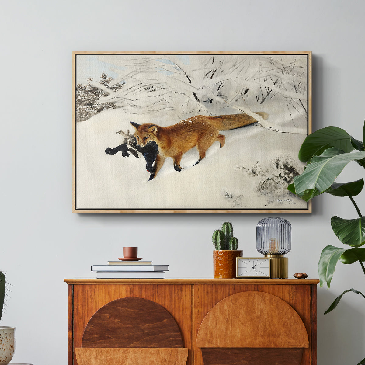 Fox in Snow Landscape, 1900 by Bruno Liljefors in a natural wood floater framed canvas featuring a fox running across snowy landscape with sparse vegetation, displayed above a wood console cabinet.