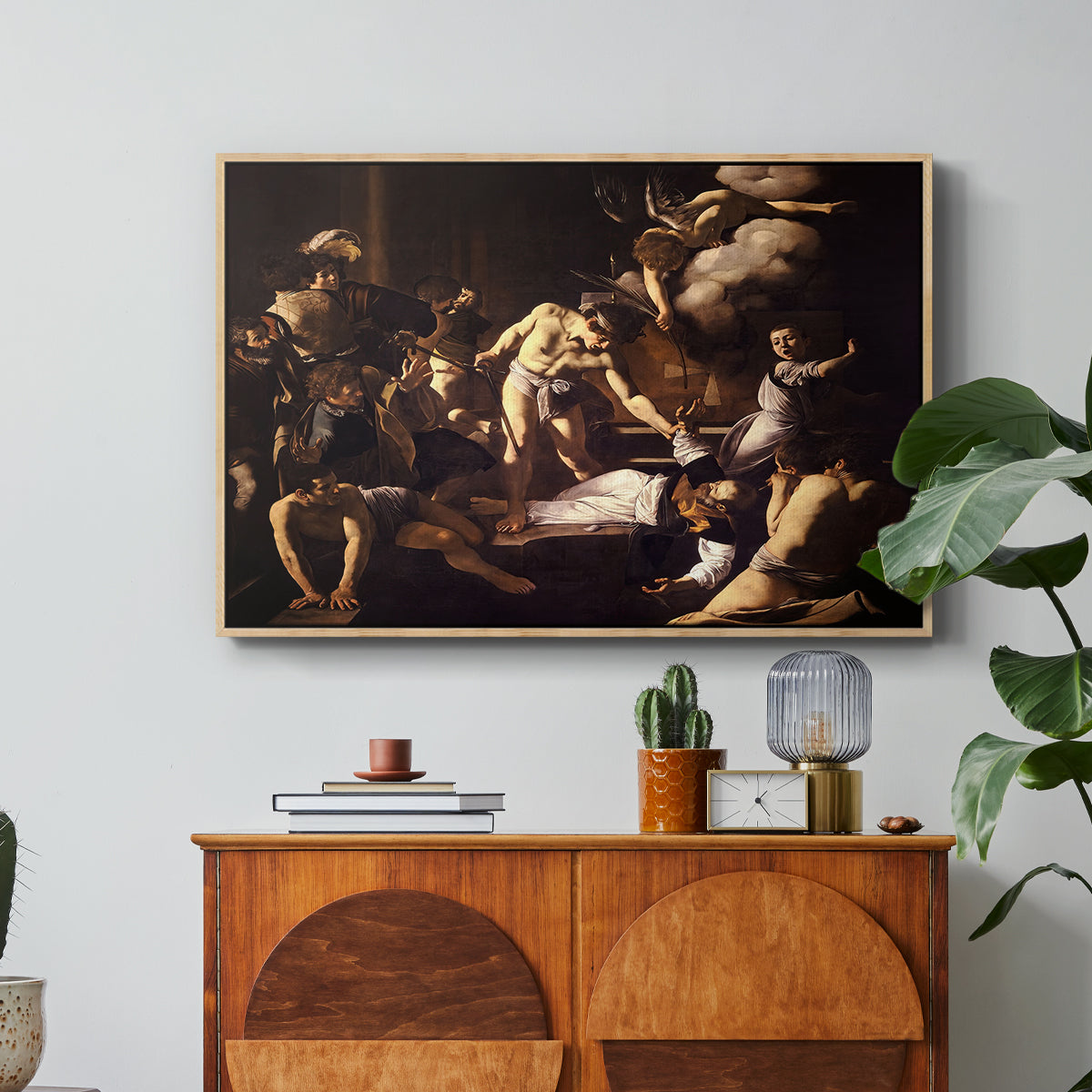 The Martyrdom of Saint Matthew, 1599-1600 by Caravaggio in a natural wood floater framed canvas featuring a chaotic scene of Saint Matthew being attacked by executioner in church, displayed above a wood console cabinet.