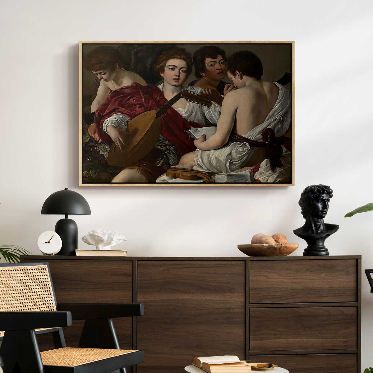 The Musicians, c. 1595 by Caravaggio displayed in a natural wood floater framed canvas above a dark wood credenza in an entryway.