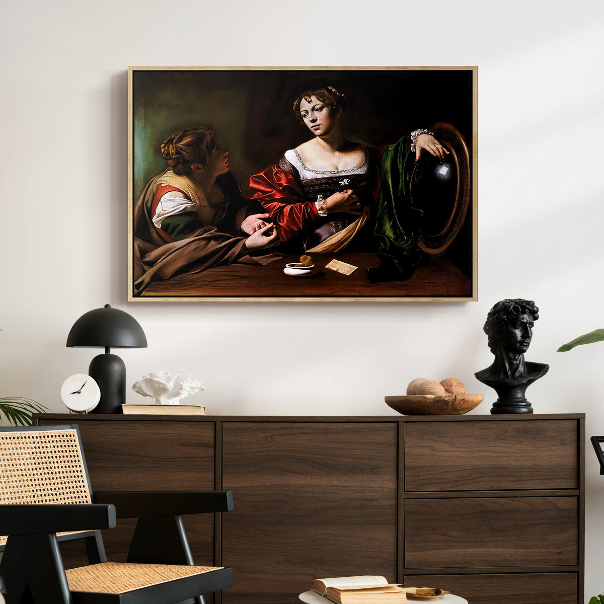 Martha and Mary Magdalene, c. 1598 by Caravaggio displayed in a natural wood floater framed canvas above a dark wood credenza in an entryway.