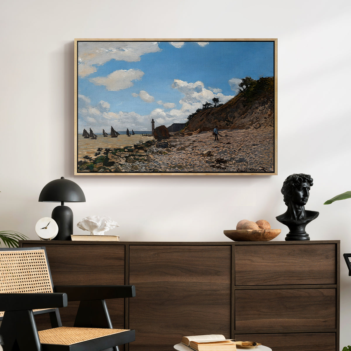 The Beach at Honfleur, 1864 by Claude Monet displayed in a natural wood floater framed canvas above a dark wood credenza in an entryway.