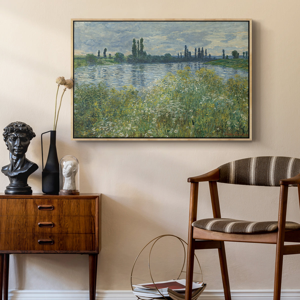 Banks of the Seine, Vétheuil, 1880 by Claude Monet as a natural wood floater framed canvas featuring a tranquil riverside scene with houses and vegetation, styled above a mid-century console in a contemporary living area.