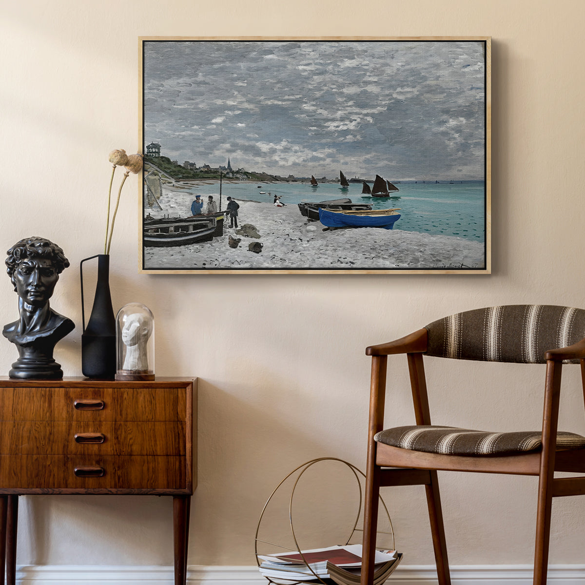 The Beach at Sainte-Adresse, 1867 by Claude Monet as a natural wood floater framed canvas featuring a coastal landscape with sailboats and visitors on cliffside, styled above a mid-century console in a contemporary living area.