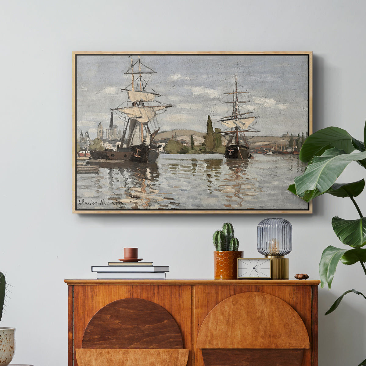 Ships Riding on the Seine at Rouen, 1872 by Claude Monet in a natural wood floater framed canvas featuring large ships docked along the Seine with masts rising against soft sky, displayed above a wood console cabinet.