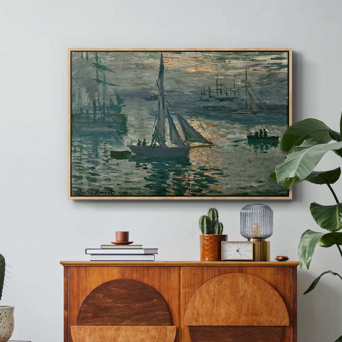 Sunrise (Marine), 1873 by Claude Monet in a natural wood floater framed canvas featuring a hazy sunrise over harbor with boats silhouetted in soft morning light, displayed above a wood console cabinet.