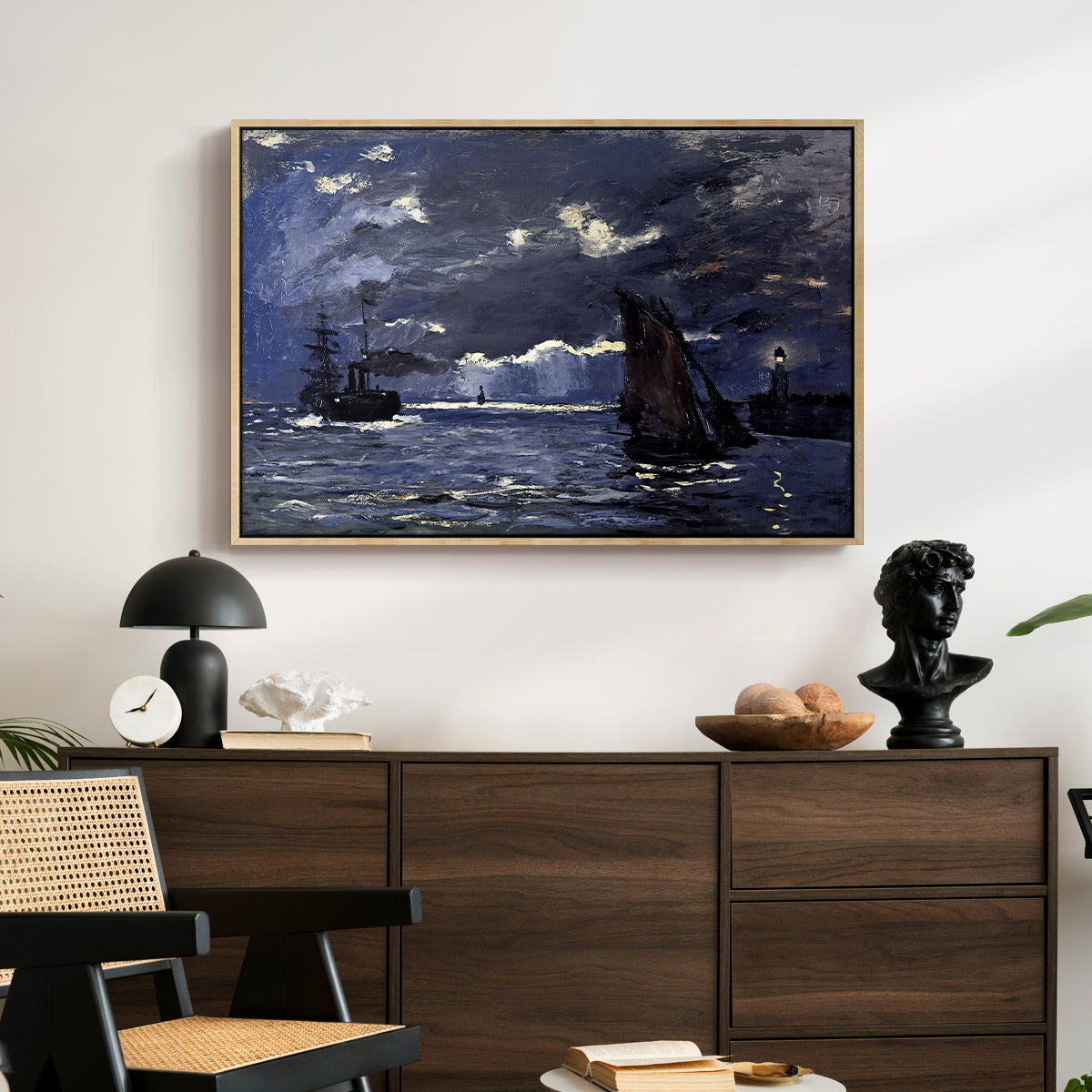 A Seascape, Shipping by Moonlight, 1864 by Claude Monet displayed in a natural wood floater framed canvas above a dark wood credenza in an entryway.