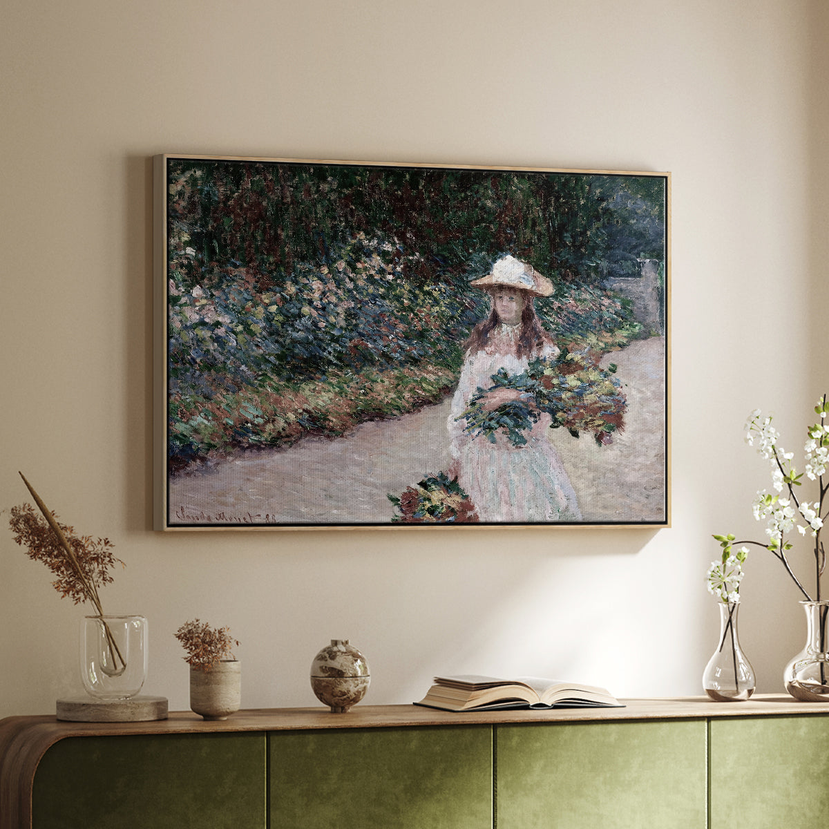 Natural wood floater framed canvas of Young Girl in the Garden at Giverny, 1888 by Claude Monet, featuring an impressionist garden scene with child among greenery and blossoms above a sideboard in a softly lit hallway.
