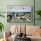 Natural wood floater framed canvas featuring a landscaped terrace with figures and flags near shoreline, displayed above a sofa in a modern living room.