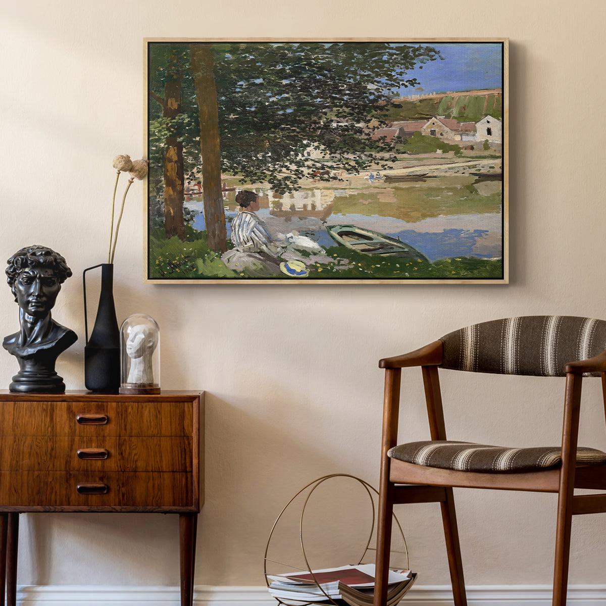 On the Bank of the Seine, Bennecourt, 1868 by Claude Monet as a natural wood floater framed canvas featuring an impressionist landscape with people relaxing along the Seine, styled above a mid-century console in a contemporary living area.