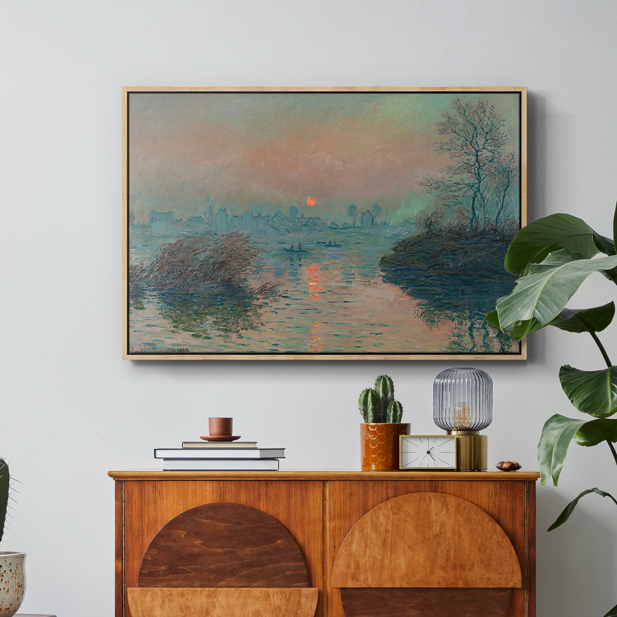 Sunset on the Seine at Lavacourt, Winter Effect, 1880 by Claude Monet in a natural wood floater framed canvas featuring a glowing sunset over snowy river landscape with soft reflections, displayed above a wood console cabinet.