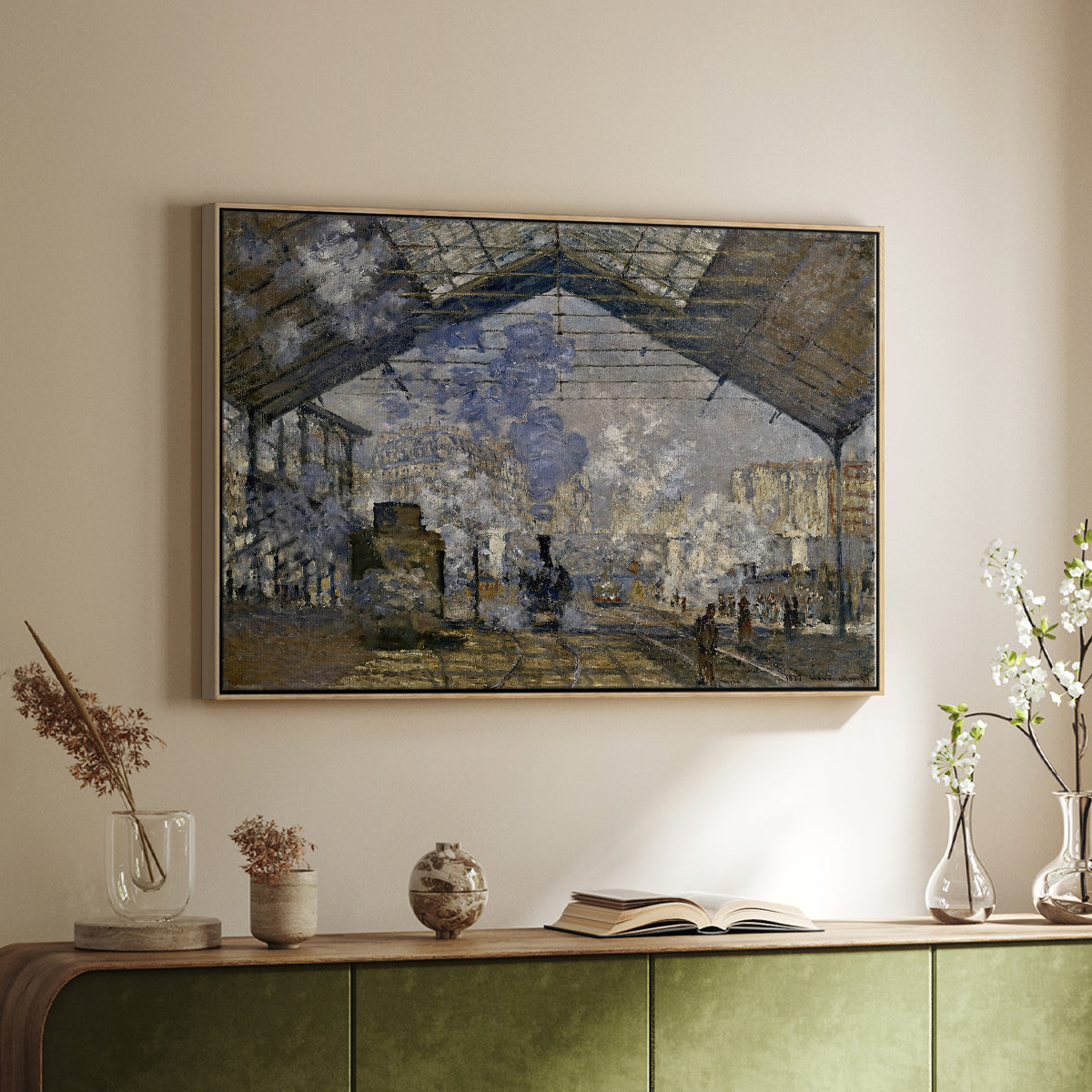 Natural wood floater framed canvas of The Gare Saint-Lazare, 1877 by Claude Monet, featuring an impressionist scene of trains and smoke inside busy railway station above a sideboard in a softly lit hallway.