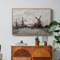 Windmills near Zaandam, 1871 by Claude Monet in a natural wood floater framed canvas featuring windmills standing beside water under open sky in rural landscape, displayed above a wood console cabinet.