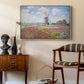 Tulip Fields with the Rijnsburg Windmill, 1886 by Claude Monet as a natural wood floater framed canvas featuring an impressionist field of blooming tulips under bright sky, styled above a mid-century console in a contemporary living area.
