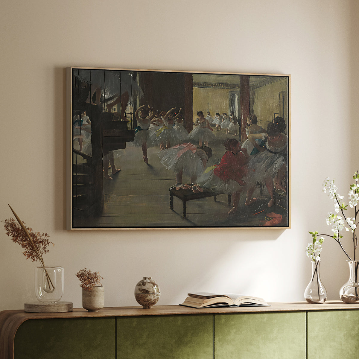 Natural wood floater framed canvas of The Dance Class, c. 1873 by Edgar Degas, featuring a rehearsal scene with dancers stretching and posing indoors above a sideboard in a softly lit hallway.
