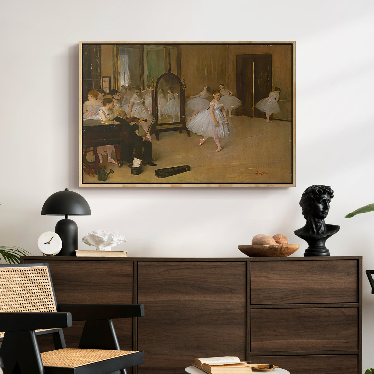 The Dancing Class, c. 1870 by Edgar Degas displayed in a natural wood floater framed canvas above a dark wood credenza in an entryway.