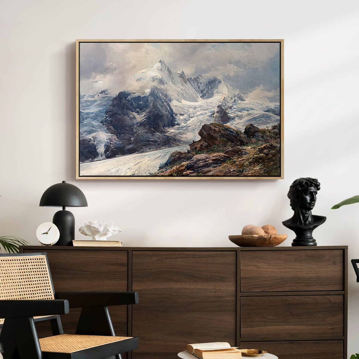 The Grossglockner, 1880 by Edward Theodore Compton displayed in a natural wood floater framed canvas above a dark wood credenza in an entryway.