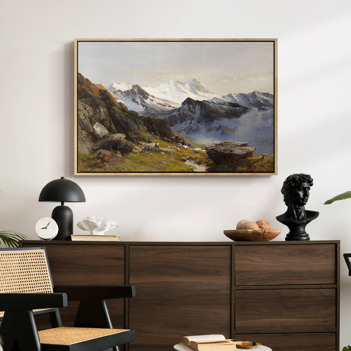 The Großglockner from the Prager Hut, 1890 by Edward Theodore Compton displayed in a natural wood floater framed canvas above a dark wood credenza in an entryway.