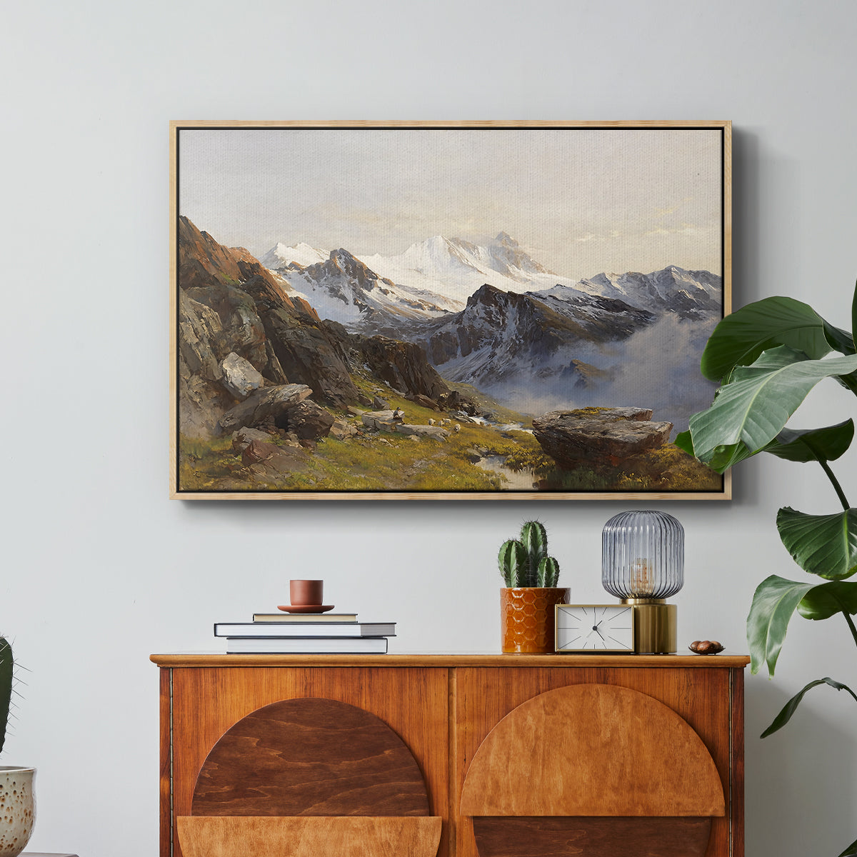 The Großglockner from the Prager Hut, 1890 by Edward Theodore Compton in a natural wood floater framed canvas featuring a view of Großglockner peak from alpine hut overlooking valley, displayed above a wood console cabinet.