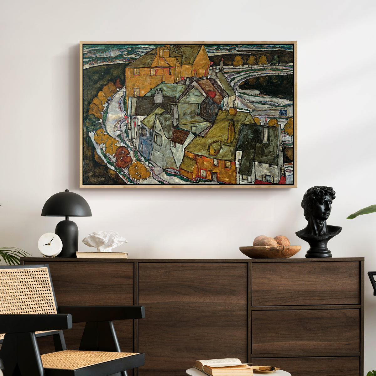 Crescent of Houses II (Island Town), 1915 by Egon Schiele displayed in a natural wood floater framed canvas above a dark wood credenza in an entryway.
