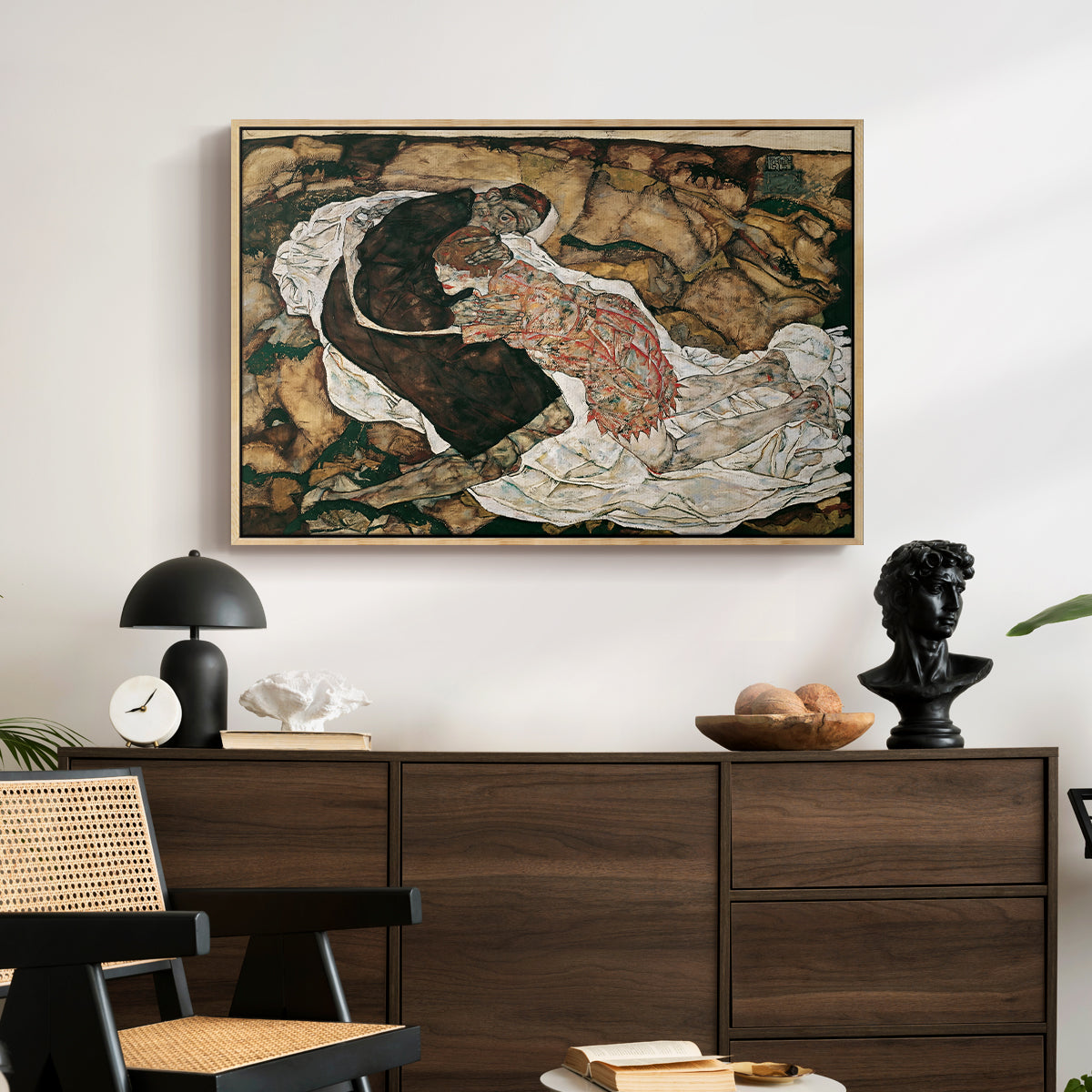 Death and the Maiden, 1915 by Egon Schiele displayed in a natural wood floater framed canvas above a dark wood credenza in an entryway.