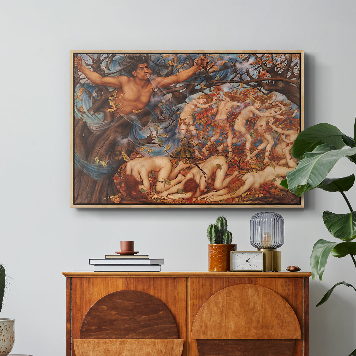 Boreas and the Fallen Leaves, c. 1910-1914 by Evelyn De Morgan in a natural wood floater framed canvas featuring swirling figures carried by wind among falling leaves in dynamic composition, displayed above a wood console cabinet.