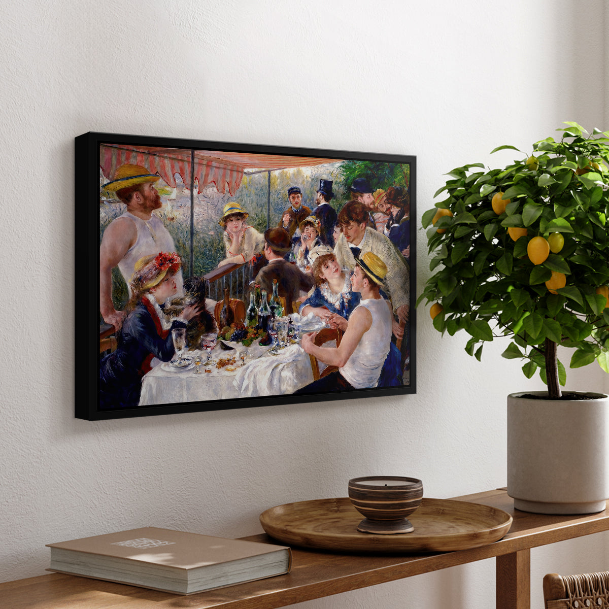 Luncheon of the Boating Party (Le Déjeuner des canotiers), 1880-1881 by Pierre-Auguste Renoir, presented in a black floater framed canvas featuring a group of elegantly dressed people dining together on a sunlit balcony overlooking the river, displayed above a hallway console table.