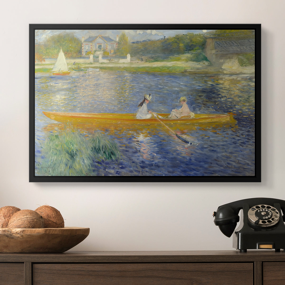 The Skiff (La Yole), 1875 by Pierre-Auguste Renoir in a black floater framed canvas displayed above a console table in a hallway, featuring a leisure scene of figures in a small rowboat on tranquil water.