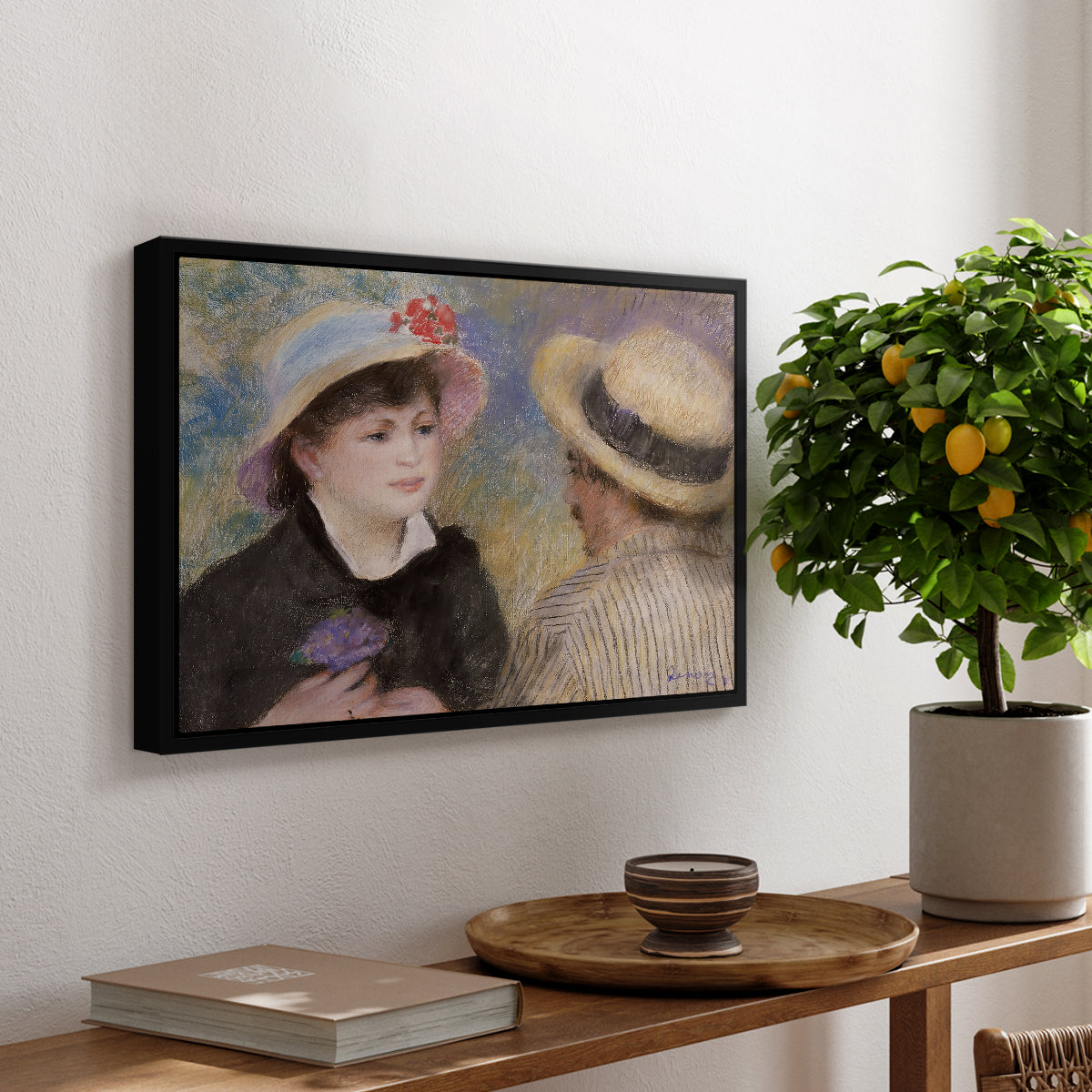 Boating Couple (Aline Charigot and Renoir), c. 1881 by Pierre-Auguste Renoir, presented in a black floater framed canvas featuring a close-up of a couple seated together outdoors with hats and soft sunlight, displayed above a hallway console table.