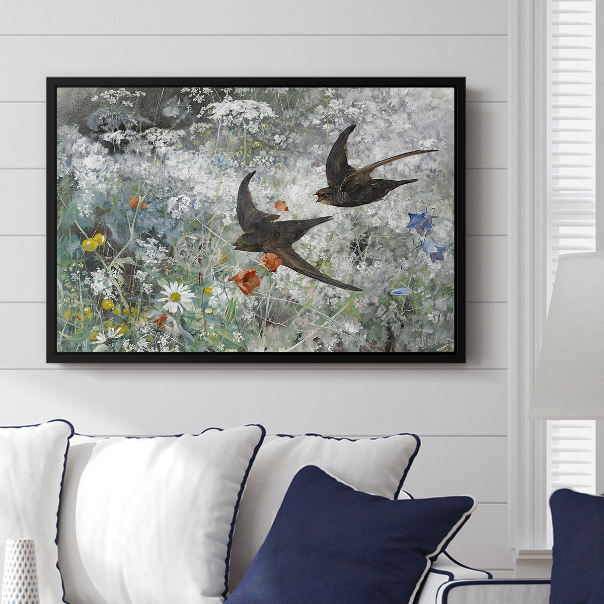Common Swifts, 1886 by Bruno Liljefors displayed above a sofa in a living room in a black floater frame, featuring swifts gliding midair with wings spread against soft sky.