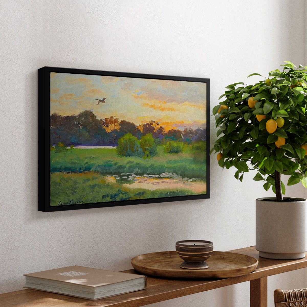 Flying Duck at Sunset, 1924 by Bruno Liljefors, presented in a black floater framed canvas featuring a wild duck flying over a sunset marsh with trees, displayed above a hallway console table.