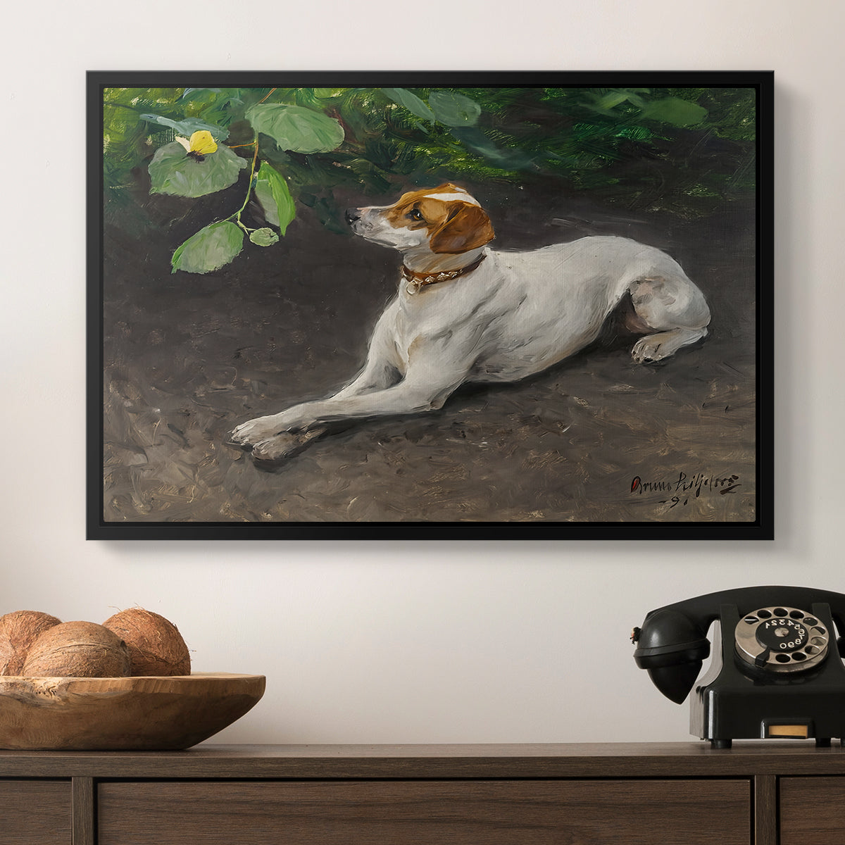 Portrait of a Dog, 1891 by Bruno Liljefors in a black floater framed canvas displayed above a console table in a hallway, featuring a calm scene of dog reclining in open landscape.