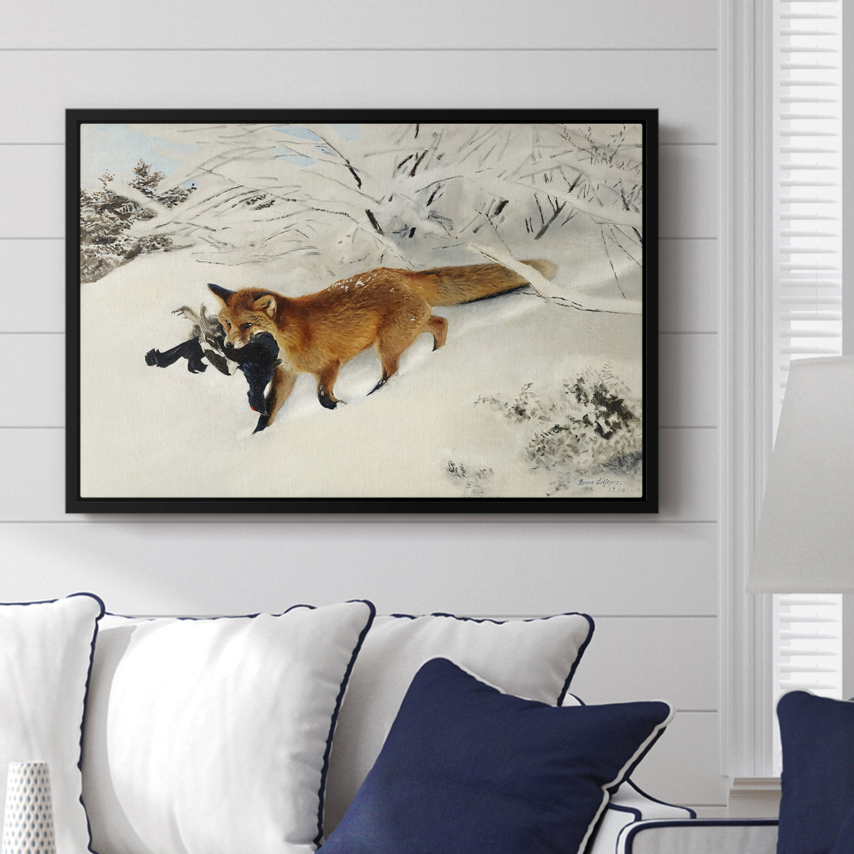 Fox in Snow Landscape, 1900 by Bruno Liljefors displayed above a sofa in a living room in a black floater frame, featuring a wildlife scene of fox moving swiftly through winter terrain.