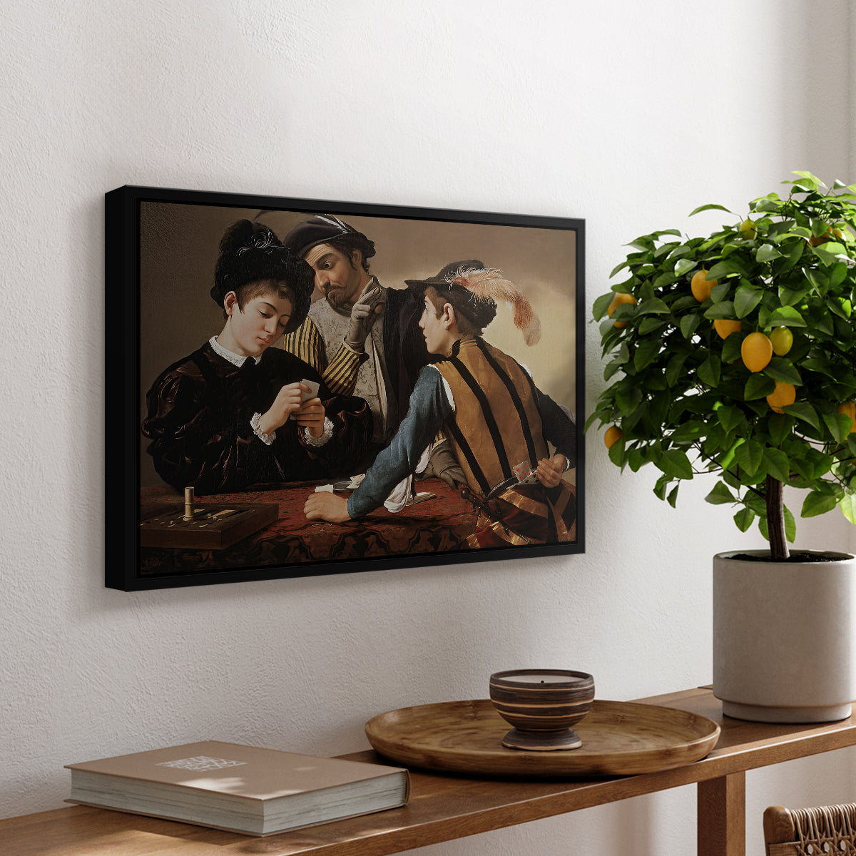 The Cardsharps, c. 1594 by Caravaggio, presented in a black floater framed canvas featuring two men cheating at cards while a third figure secretly observes behind them, displayed above a hallway console table.