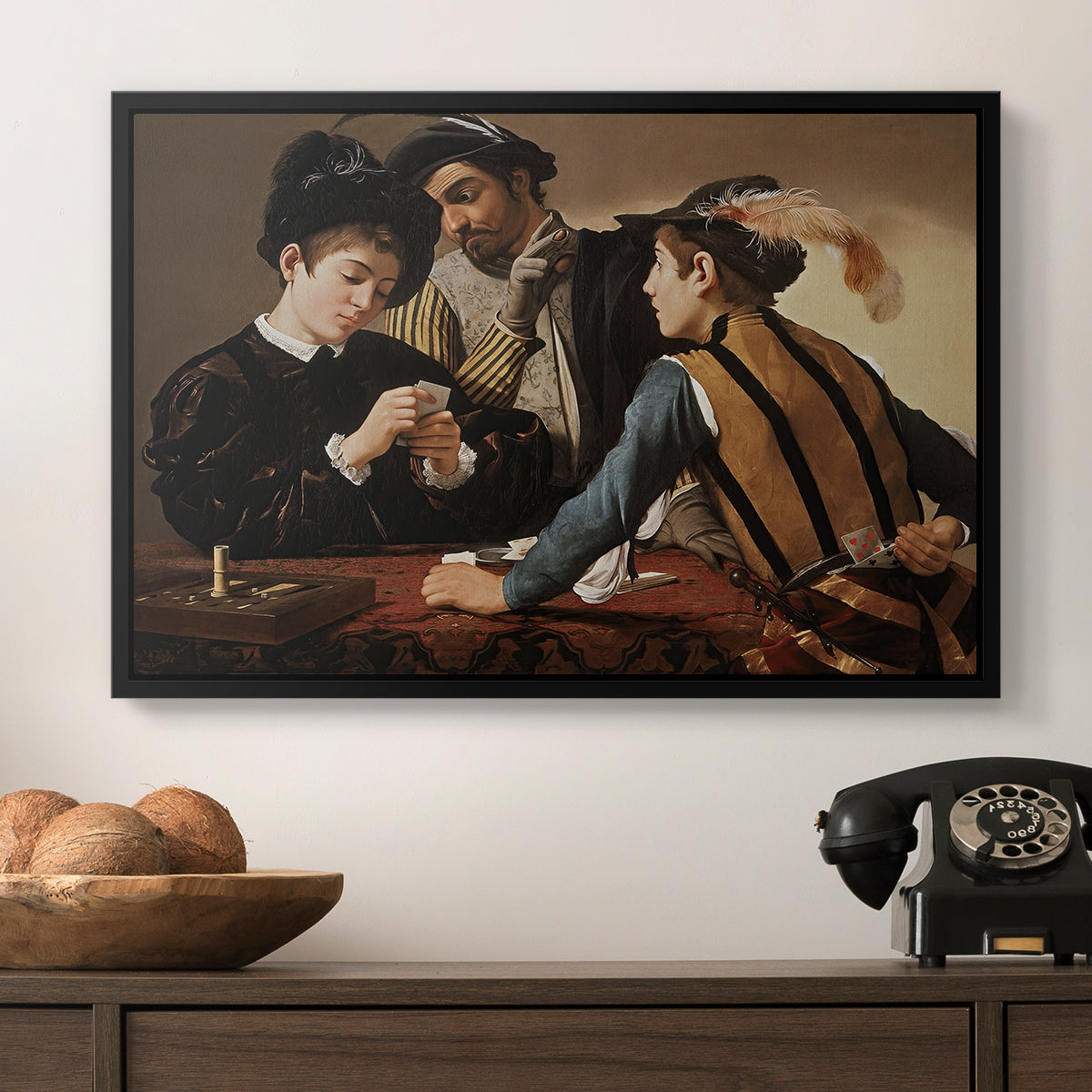 The Cardsharps, c. 1594 by Caravaggio in a black floater framed canvas displayed above a console table in a hallway, featuring a dramatic interior scene of gambling and trickery among figures.