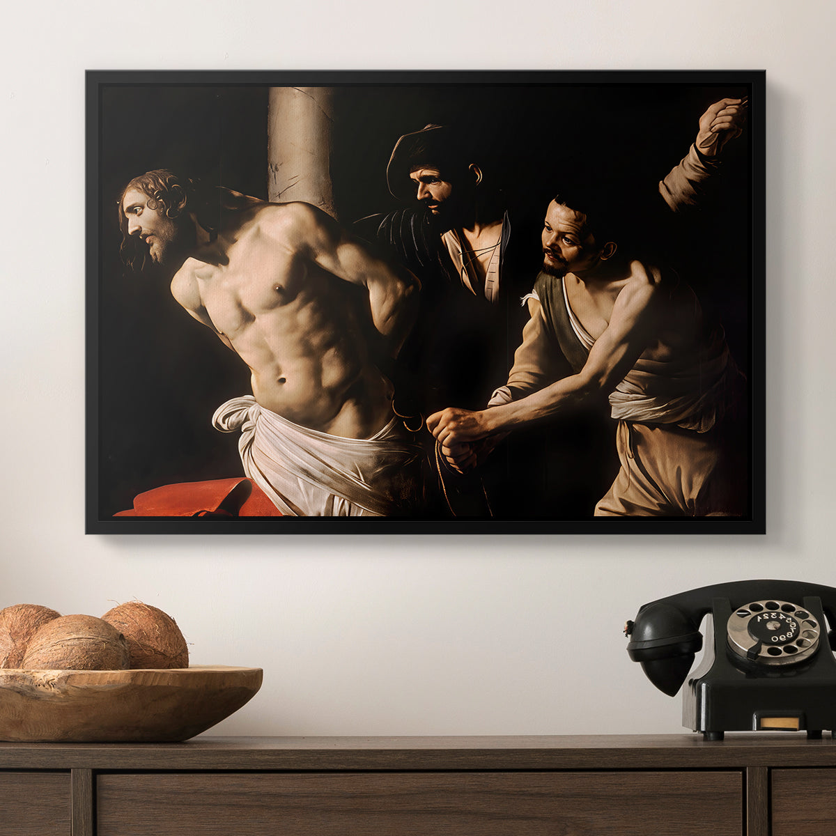 The Flagellation of Christ at the Column (Rouen Version), 1606 by Caravaggio in a black floater framed canvas displayed above a console table in a hallway, featuring an intense Baroque scene of suffering with strong light and shadow.