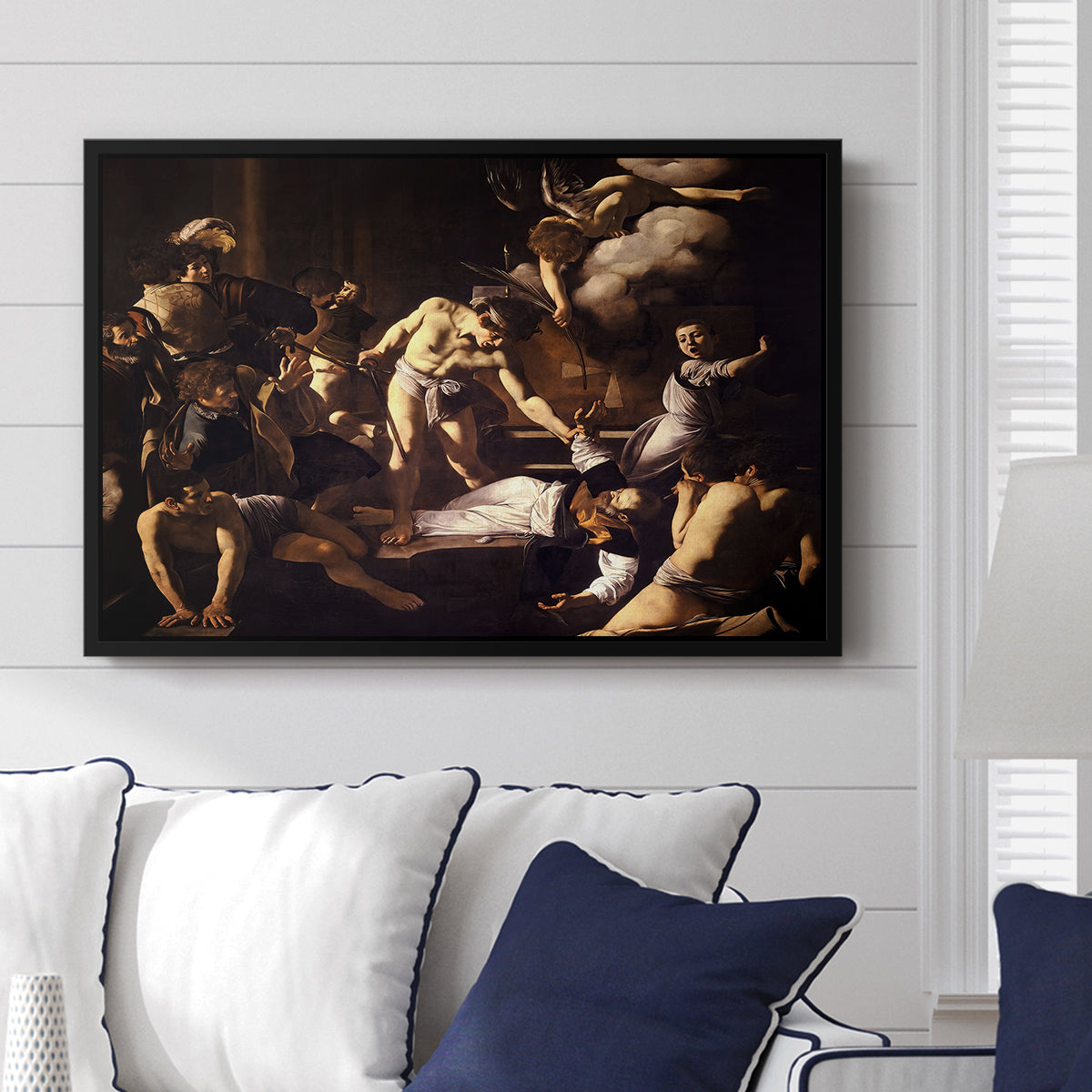 The Martyrdom of Saint Matthew, 1599-1600 by Caravaggio displayed above a sofa in a living room in a black floater frame, featuring a dramatic moment of martyrdom with figures reacting in panic.