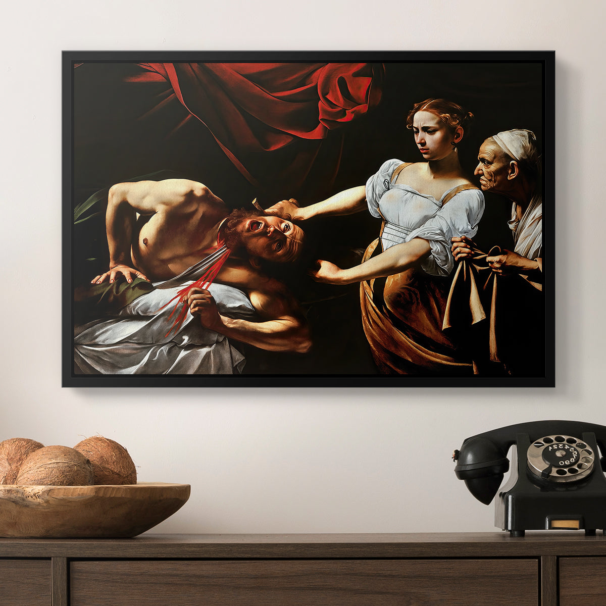 Judith Beheading Holofernes, c. 1599 by Caravaggio in a black floater framed canvas displayed above a console table in a hallway, featuring a violent religious narrative with strong contrast of light and shadow.
