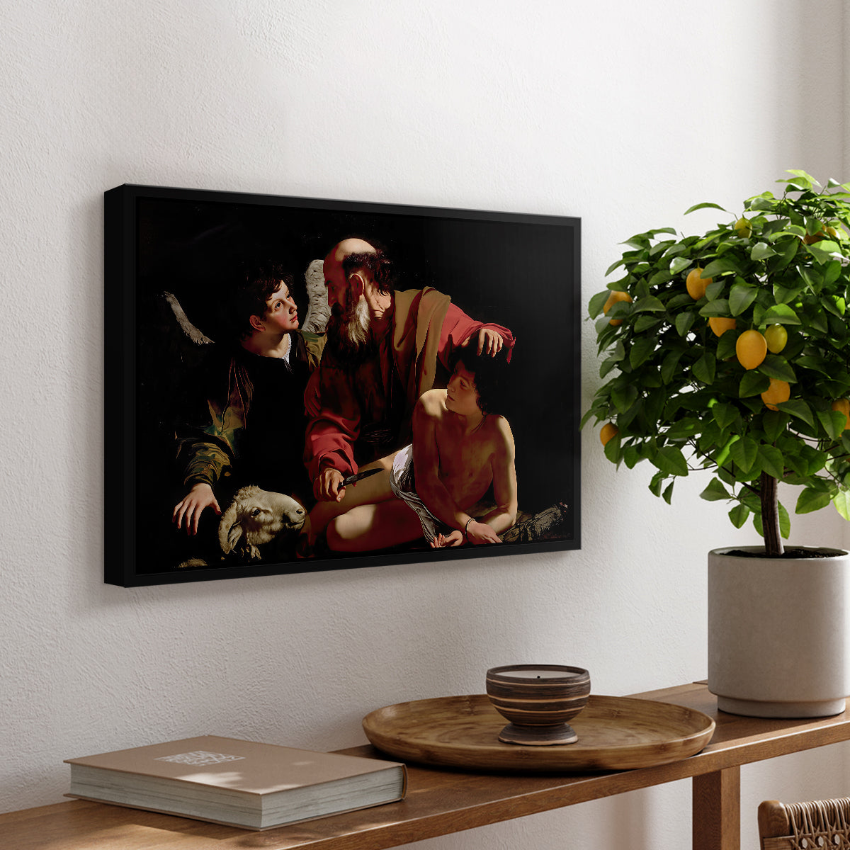 The Sacrifice of Isaac (Uffizi Version), c. 1603 by Caravaggio, presented in a black floater framed canvas featuring Abraham holding Isaac while angel intervenes to stop the sacrifice, displayed above a hallway console table.