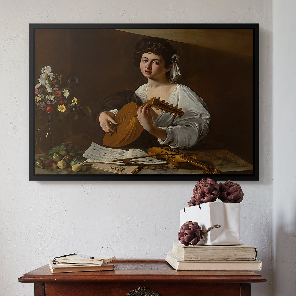 Black floater framed canvas featuring The Lute Player (Hermitage Version), c. 1596 by Caravaggio above an entryway table in a minimalist foyer.