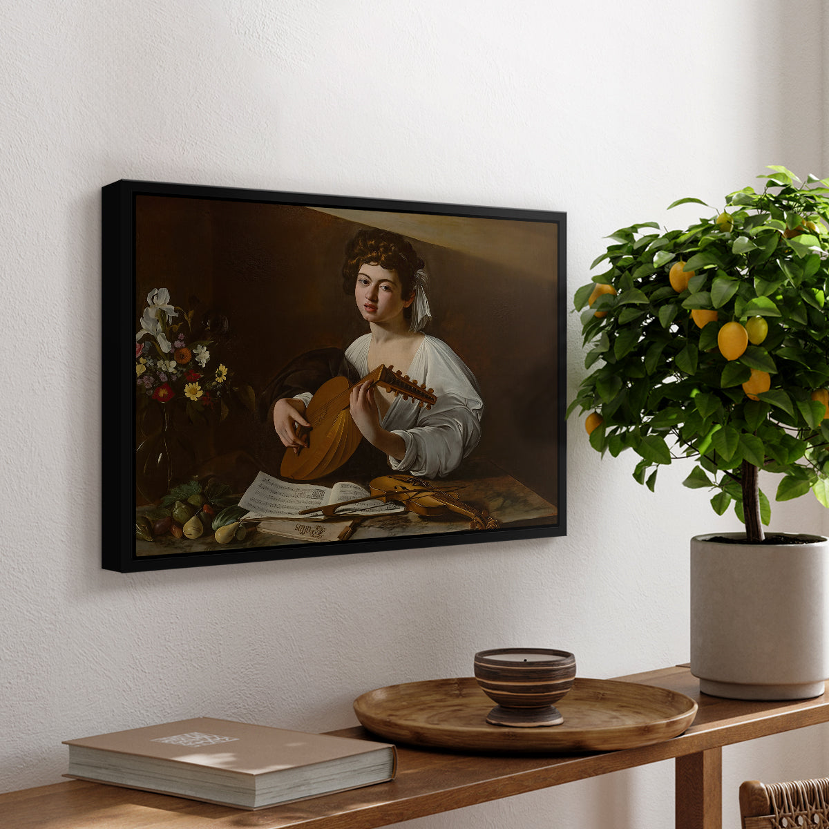 The Lute Player (Hermitage Version), c. 1596 by Caravaggio, presented in a black floater framed canvas featuring a young musician playing lute beside table with fruit and sheet music, displayed above a hallway console table.