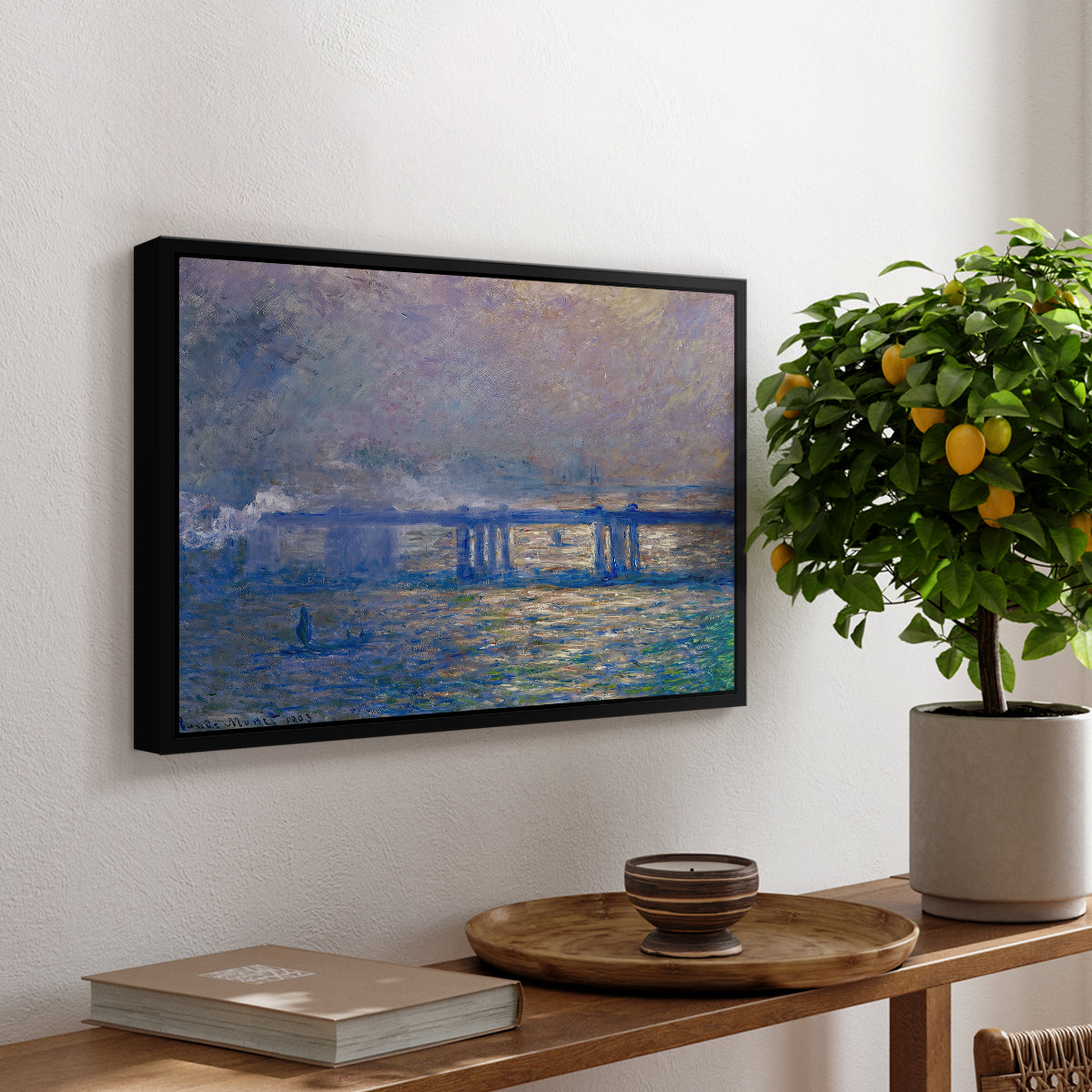 Charing Cross Bridge, 1903 by Claude Monet, presented in a black floater framed canvas featuring an impressionist view of bridge stretching across river with soft light and haze, displayed above a hallway console table.