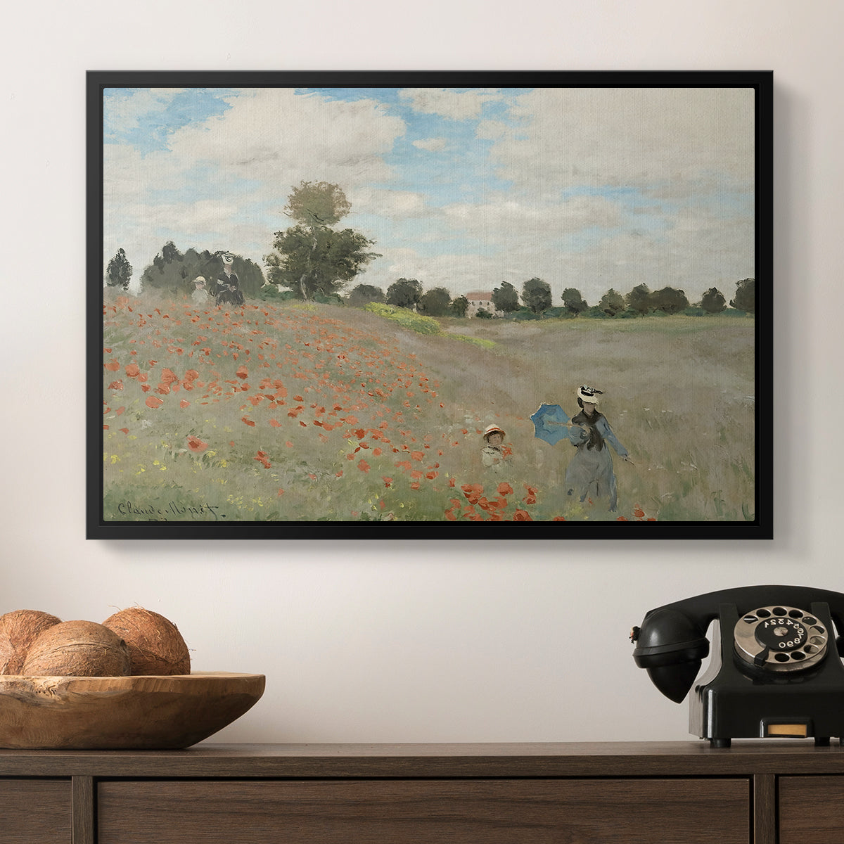 The Poppy Field near Argenteuil, 1873 by Claude Monet in a black floater framed canvas displayed above a console table in a hallway, featuring a rural landscape with scattered figures among blooming flowers.