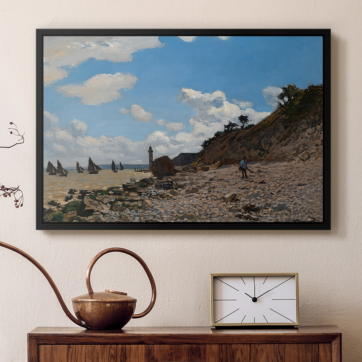 Black floater framed canvas featuring a sandy beach with figures relaxing near water's edge, displayed above a cabinet in a soft-toned living room.